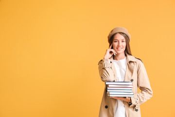 Poster - Beautiful young woman with books on color background