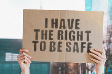The Phrase " I Have The Right To Be Safe " On A Banner In Men's Hand With Blurred Background. Safety. Security. Dangerous. Government. Protection. Privacy. Safeguard