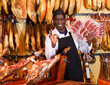 Modern owner of butcher shop selling traditional spanish jamon
