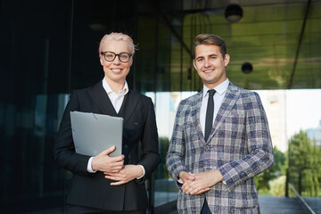 Wall Mural - Portrait of successful business couple smiling at camera while standing together outdoors