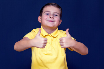 Nice young 9s boy shows a class with two thumbs up on a blue wall.