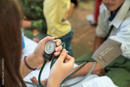 Fotografía Volunteer nurse measuring blood pressure of poor Asian people outdoors closeup