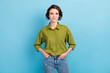 Photo of pretty confident lady short hairstyle happy cheerful look camera hands pockets wear denim jeans green shirt isolated blue color background