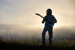 © anatoliy_gleb - Silhouette of space traveler playing melody on guitar in misty grassy valley with white mystical sky on background. Cosmonaut guitarist with musical instrument wearing while space suit and helmet.