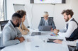 © Sanja - A group of business partners sit in a conference room and analyze business, read data from laptops