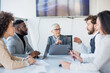 © Sanja - A group of business partners sit in a conference room, employees suggest new idea in making a profit, others listen