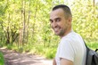 © Анастасия Семашко - Smiling traveler with a backpack walking in the forest, rear view
