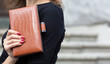 Woman holding brown leather clutch