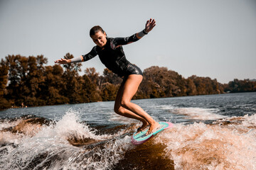 Wall Mural - girl riding wave on surf style wakeboard and lifting up lot of splashes