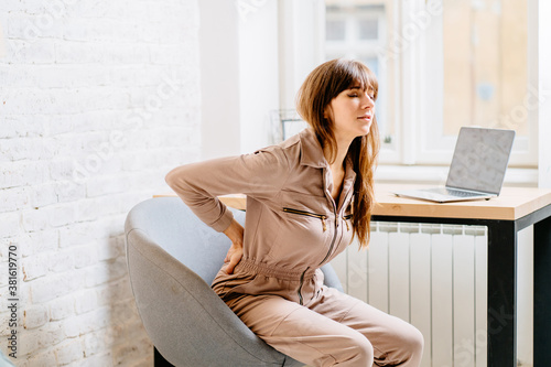 Cuadros en Lienzo Side view of beautiful brunette woman freelancer suffering from back pain in home office
