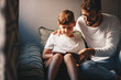 © Sanja - Father and son sit on the couch during the afternoon, flipping through the book together