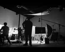 Behind The Scene Of Photo Shooting And Production Set Up In The Big Studio. Professional Crew Team Working And Camera Equipment In Silhouette. Such As Light Box, Tripod, Flashlight. And Copy Space.