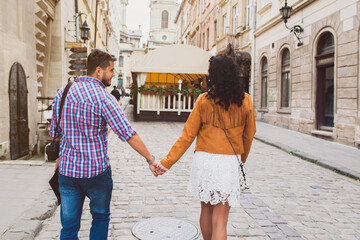 young couple in love traveling, vintage style, europe vacation, honey moon, old city center, happy positive mood, holding hands, walking together in street, view from back