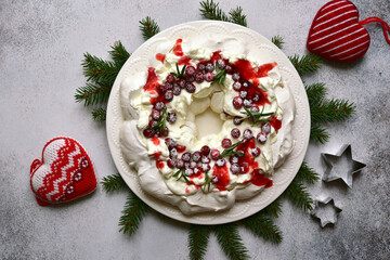 Christmas meringue cake Pavlova with cranberry and rosemary . Top view with copy space.