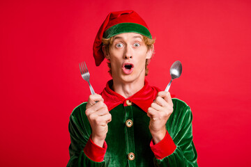 Photo of amazed elf guy hold spoon fork x-mas christmas party feast concept isolated over red shine color background