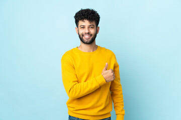 Young Moroccan man isolated on blue background giving a thumbs up gesture