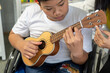 © suwanb - Beautiful teacher teaching students with disabilities to play the guitar.