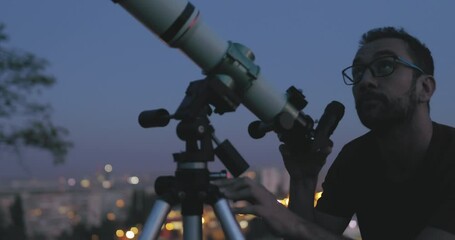 Wall Mural - astronomer with a telescope watching at the stars and moon with blurred city lights in the backgroun