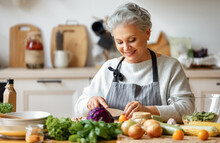 Happy Mature Woman Preparing Healthy Salad In Kitchen