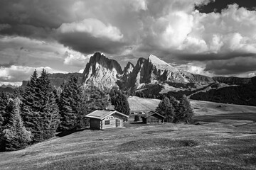 Wall Mural - Famous Alpe di Siusi - Seiser Alm with Sassolungo - Langkofel mountain group in background at sunset. Wooden chalets in Dolomites, Trentino Alto Adige region, South Tyrol, Italy