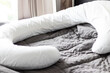 White Pregnancy pillow on a bed for pregnant woman to sleep comfort