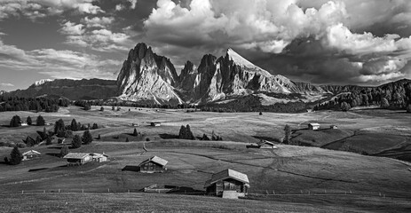 Wall Mural - Famous Alpe di Siusi - Seiser Alm with Sassolungo - Langkofel mountain group in background at sunset. Wooden chalets in Dolomites, Trentino Alto Adige region, South Tyrol, Italy