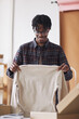 © AnnaStills - African man unpacking the parcel and pulling out the new shirt he is happy of his online order