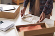 © AnnaStills - Close-up of man packing new clothes into the cardboard box at the table