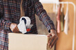 © AnnaStills - Close-up of delivery man packing cardboard box with adhesive tape before delivering