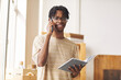 © AnnaStills - Portrait of African young man working on digital tablet and taking the order by the phone