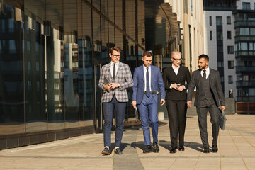 Wall Mural - Group of business people discussing work while walking along the city street