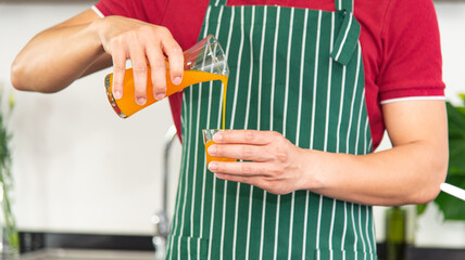 Portrait smart and handsome Asian man preparing healthy meal and orange juice in the loft style kitchen.