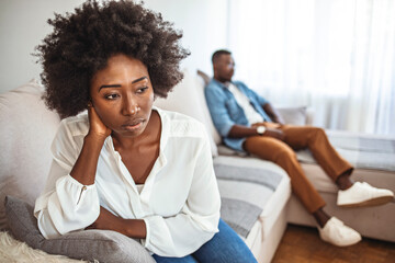 Upset couple at home. Handsome man and beautiful young woman are having quarrel. Sitting on sofa together. Family problems. I can't believe we're fighting about this again.