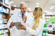 © Minerva Studio - Two pharmacists talking while working on tablet in their store