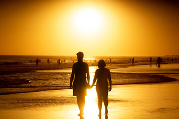 couple walking on the beach at sunset hand in hand. lovely romantic scene in Claromeco, Argentina