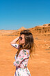 © KseniaJoyg - A young woman with long hair in a short dress walks through the orange rocky desert on a hot day