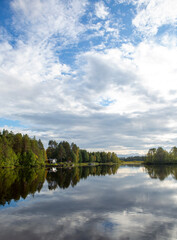 Wall Mural - Beautiful landscape in Finland at the lake shore. Reflecting waters and cloudy sky. Calm scenery for poster and wallpaper use.