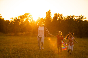 Wall Mural - happy family mother and children run on meadow with a kite in the summer on the nature