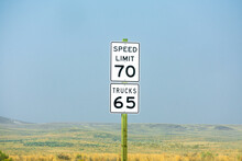 Seventy Mph Speed Limit, Trucks 65 Sign On Wooden Post. Speed Zone Traffic Sign Against Desert Landscape.