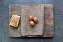 Tres Huevos Sobre Un Saco De Tela Y Tabla De Cocinar Con Un  Trozo De Pan En Una Encimera De  Cocina 