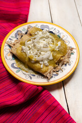 Mexican green enchiladas with chicken and cheese on white background