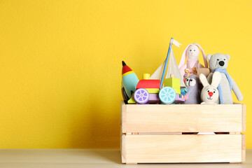 Poster - Crate with different toys on wooden table. Space for text