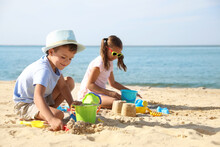 Cute Little Children Playing With Plastic Toys On Sandy Beach