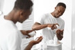 © Prostock-studio - African Man Using Shaving Foam Standing Near Mirror In Bathroom