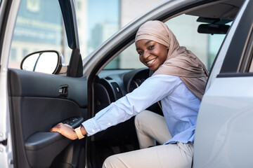 Wall Mural - New Car. Happy black muslim businesswoman getting in luxury auto and smiling