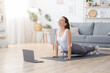 © Prostock-studio - Positive yoga woman doing morning practice in front of laptop