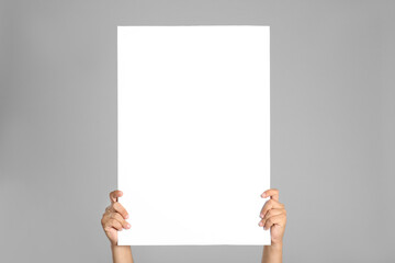 Wall Mural - man holding white blank poster on grey background, closeup. mockup for design