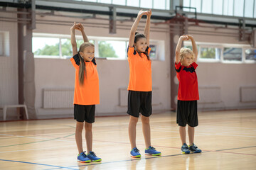 Wall Mural - Three kids doing stretching on PE lesson