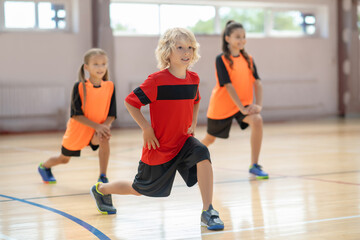 Wall Mural - Kids exercising in the gym and doing lungings forward