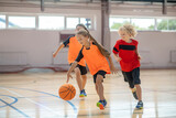Children in bright sportswear playing basketball and looking excited